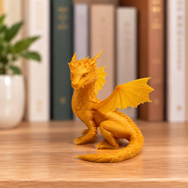 Gold baby Andarna dragon figurine on a bookshelf