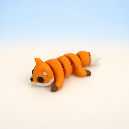 Micro Fox 3D-printed miniature featuring an orange body, dark legs, and a pale muzzle, on a light surface with a pale blue background.