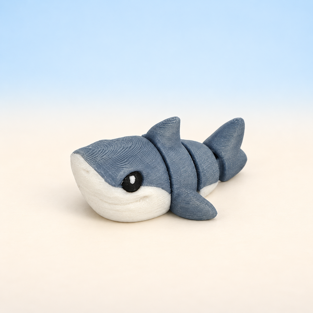Micro Great White Shark 3D-printed miniature featuring a gray body, white underside, and prominent dorsal fin, on a light surface with a pale blue background.