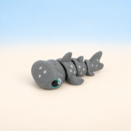 Micro Hammerhead Shark 3D-printed miniature featuring a gray body, wide hammer-shaped head, and spotted details, on a light surface with a pale blue background.
