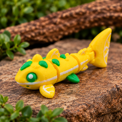 Micro Lemon Shark miniature with a yellow articulated body, green accents and white lemon details, three-quarter view on wood.