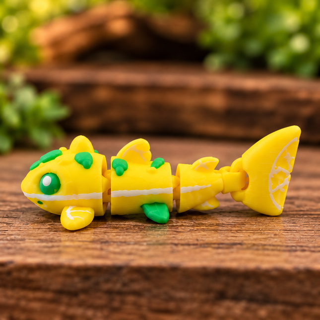 Side view of the yellow Micro Lemon Shark showing its articulated body and lemon-patterned tail on wood.