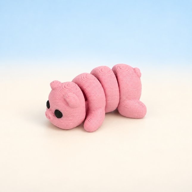 Micro Pig 3D-printed miniature featuring a pink body, rounded snout, and small ears, on a light surface with a pale blue background.