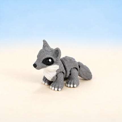 Micro Wolf 3D-printed miniature featuring a gray body, pointed ears, and pale facial markings, on a light surface with a pale blue background.
