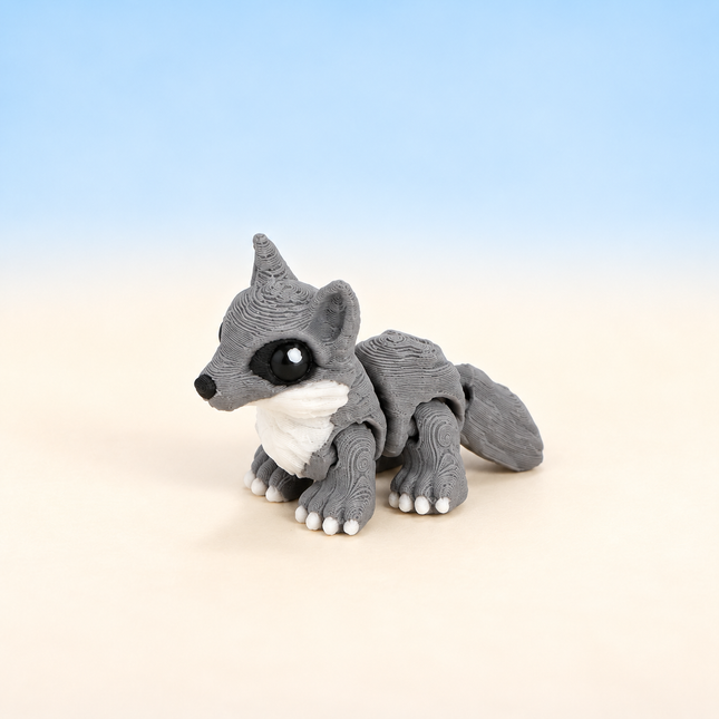 Micro Wolf 3D-printed miniature featuring a gray body, pointed ears, and pale facial markings, on a light surface with a pale blue background.
